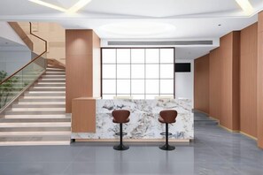 A reception area with a marble counter, two bar stools, a staircase, and a large window. - Janger Hotel (Chongqing Nanchuan branch) (Chongqing)