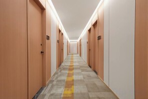 A hotel hallway with wooden doors, a patterned carpet, and overhead lighting. - Janger Hotel (Chongqing Nanchuan branch) (Chongqing)