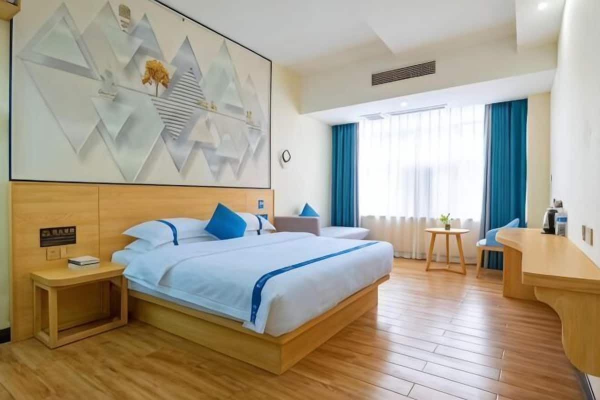 Habitación de hotel con cama, mesita de noche, escritorio y una gran obra de arte abstracta en la pared.