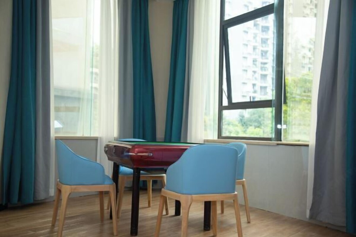 A room with a pool table, four blue chairs, and a large window with curtains.