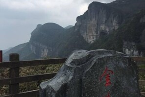 A stone monument with inscriptions, a wooden fence, and a mountainous landscape in the background. - Janger Hotel (Chongqing Nanchuan branch) (Chongqing)