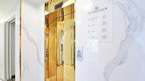 An elevator interior with a marble wall and a sign indicating hotel B's amenities. - HADAN DENBASTA HOTEL (Busan)