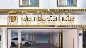 A hotel entrance with a sign reading "Den Basta hotel" and a parking garage with a white car inside. - HADAN DENBASTA HOTEL (Busan)