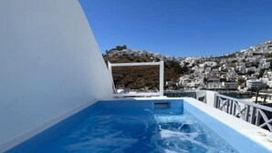 En klarblå pool med utsikt över en vitkalkad stad som ligger på en sluttning.