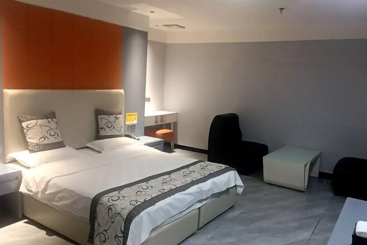 Una habitación de hotel moderna con una cama, mesitas de noche, una silla y una pequeña mesa.