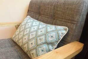 Une chaise avec un dossier rembourré de couleur grise et un accoudoir en bois.