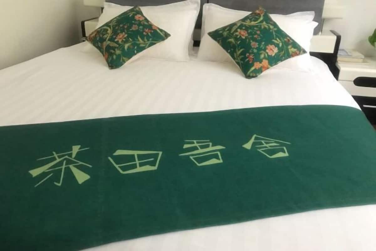 Een bed met een groene sprei en kussens met bloemenmotieven.