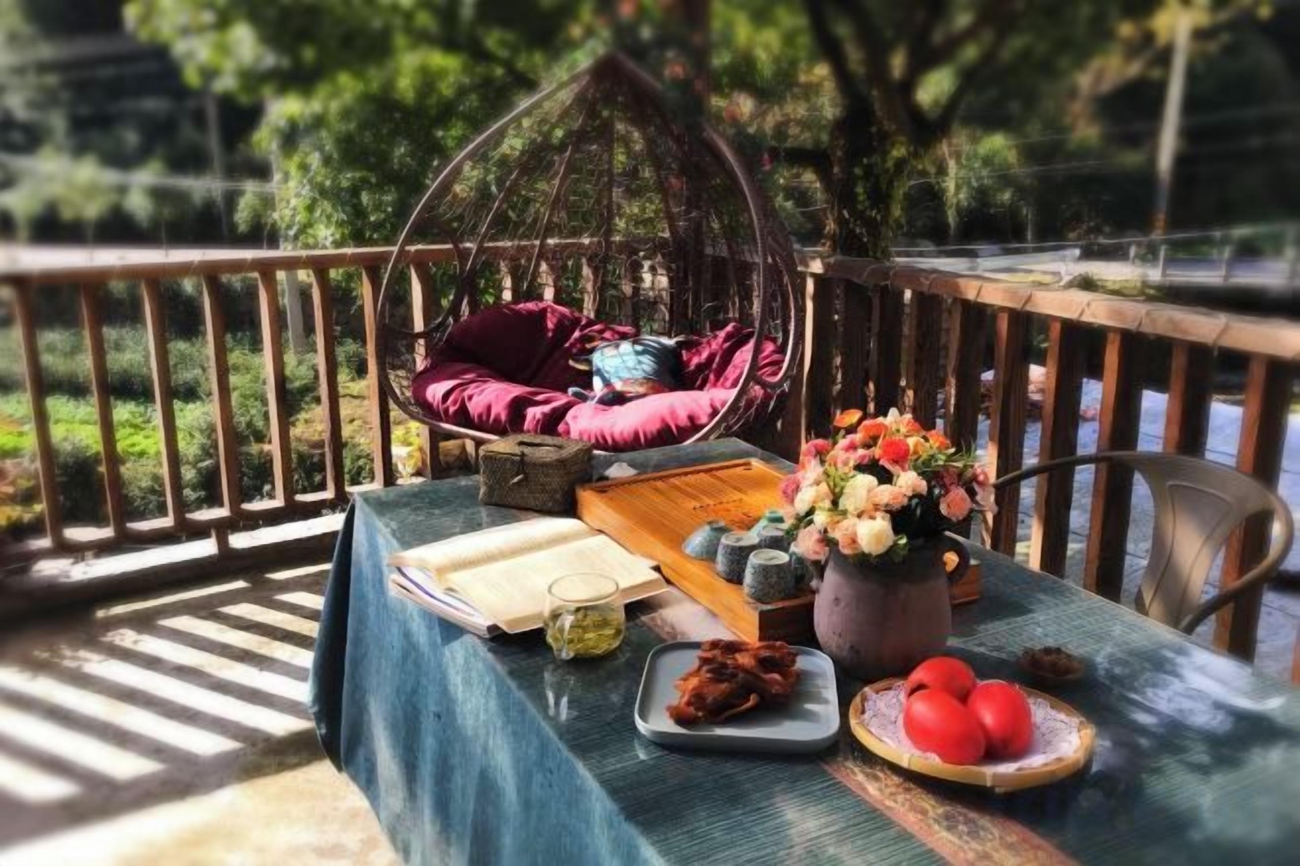 A table with a book, a vase with flowers, and a plate of food.