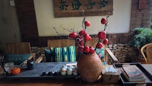 Een houten tafel met een vaas rode bessen, een dienblad met kleine keramieken voorwerpen, en een stenen muur op de achtergrond.