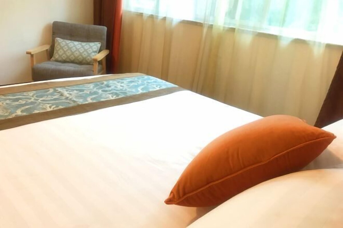 Une chambre d’hôtel avec un lit, une chaise et une fenêtre avec des rideaux.