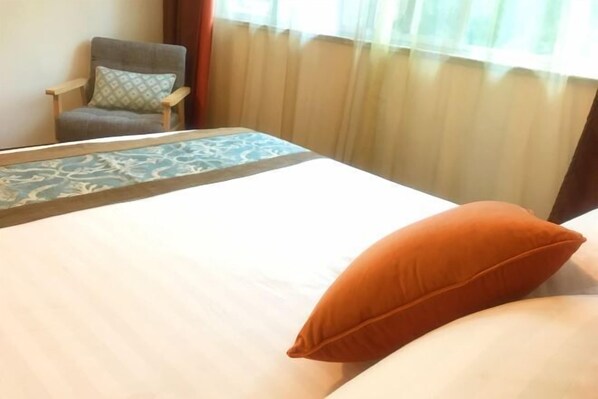 Une chambre d’hôtel avec un lit, une chaise et une fenêtre avec des rideaux.