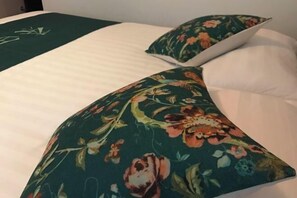 Un lit avec un coussin à motifs floraux et un plaid vert.
