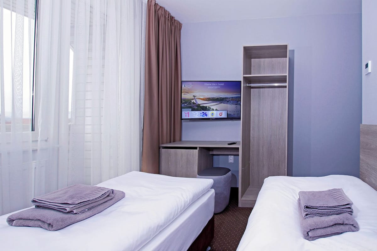 A hotel room with two beds, a TV on a stand, a desk, and a wardrobe.