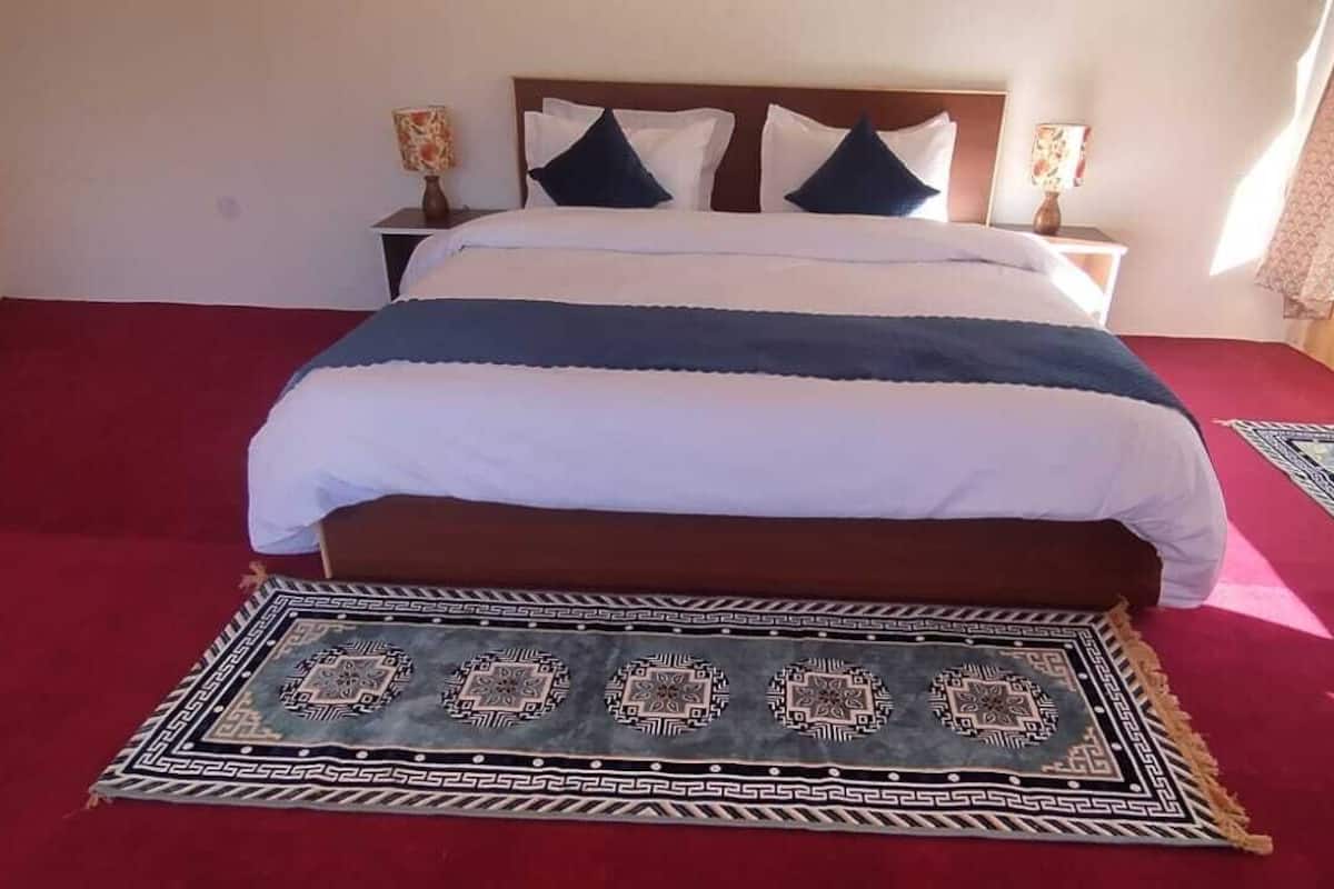 A bedroom with a large bed, two bedside tables, and a window with curtains.