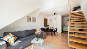 A modern living space with a grey sofa, a round coffee table, and a staircase with wooden steps. - Modern apartment on Graficka (Prague)