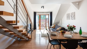 A modern interior with a staircase, dining area, and a view through a glass door. - Modern apartment on Graficka (Prague)