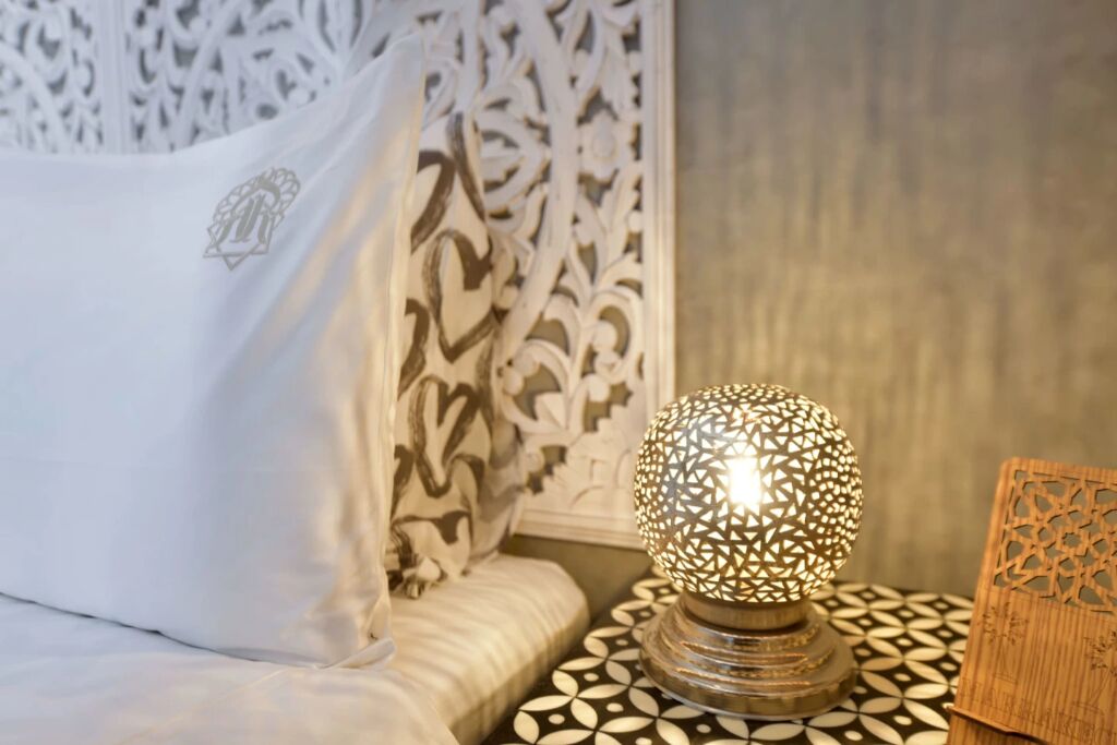 A bed with a white pillow and a decorative wall with intricate patterns.