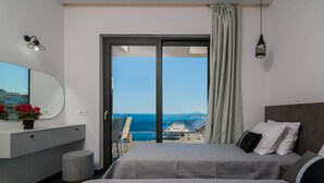 A hotel room with a bed, a desk, a chair, a small stool, and a view of the sea. - Nikolakos Villa - pirvate pool (Zakinthos)