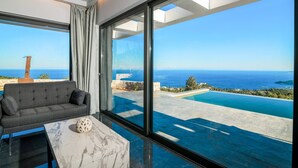 A modern room with a large window, a sofa, and a marble table. - Nikolakos Villa - pirvate pool (Zakinthos)