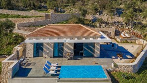 A villa with a swimming pool, stone walls, and a terrace with lounge chairs. - Nikolakos Villa - pirvate pool (Zakinthos)
