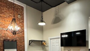 Una cucina moderna con parete in mattoni, illuminazione a sospensione, un grande televisore a schermo piatto e sgabelli da bar.