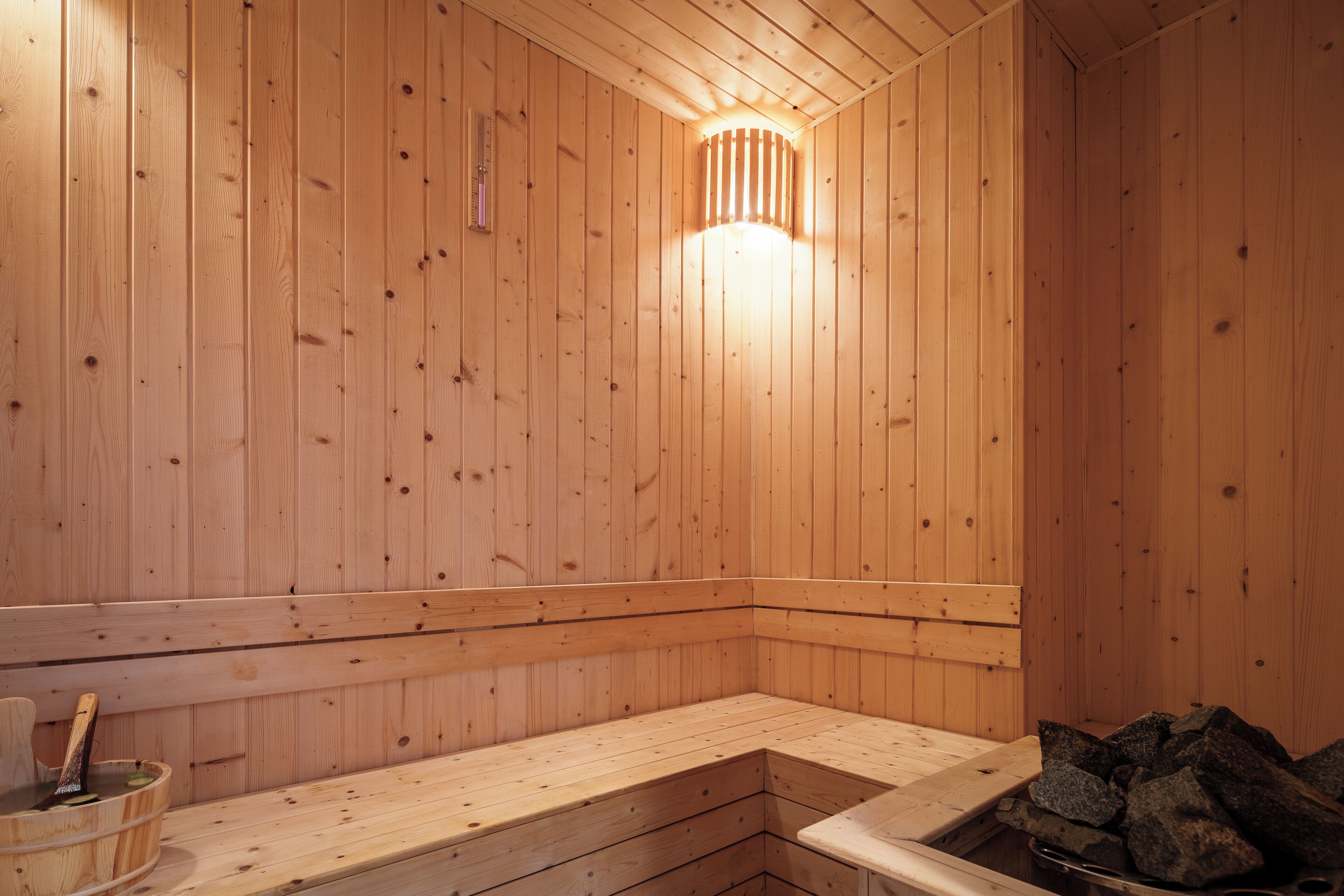 Una sauna de madera con bancos y una piedra para lavarse.