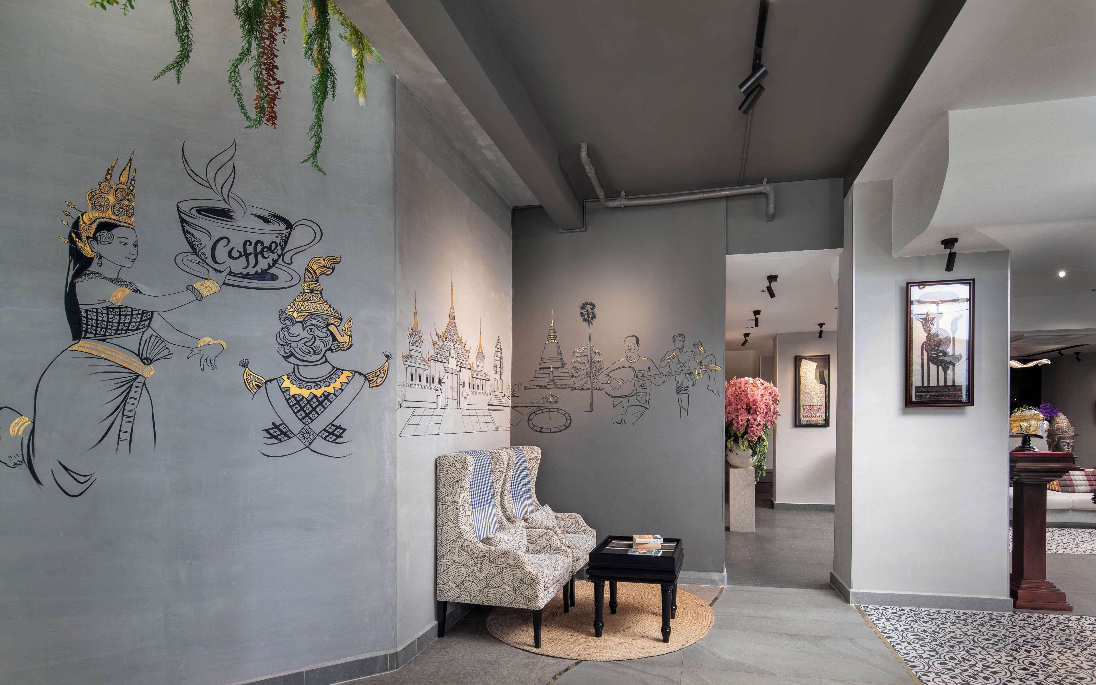 A hallway with a mural, a patterned armchair, a small table, and a potted plant.