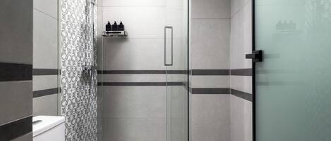 Un baño moderno con cabina de ducha de vidrio, inodoro y lavabo.