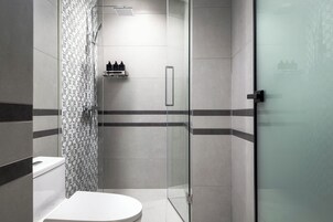 Een moderne badkamer met een douchecabine van glas, een toilet en een wastafel.