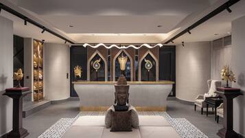 A modern lobby with a central reception desk, seating area, and decorative elements.