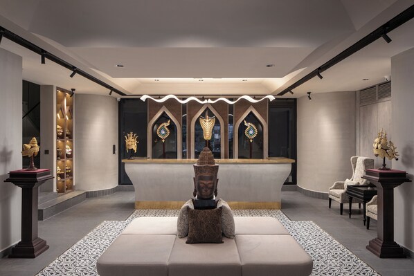 Un vestíbulo moderno con una recepción central, zona de estar y elementos decorativos.