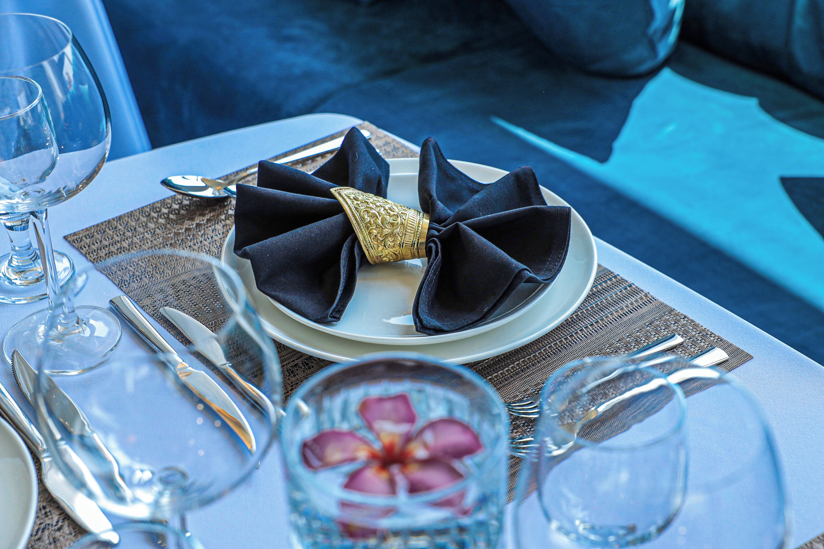 A table set with a white plate, dark napkins, and silverware.
