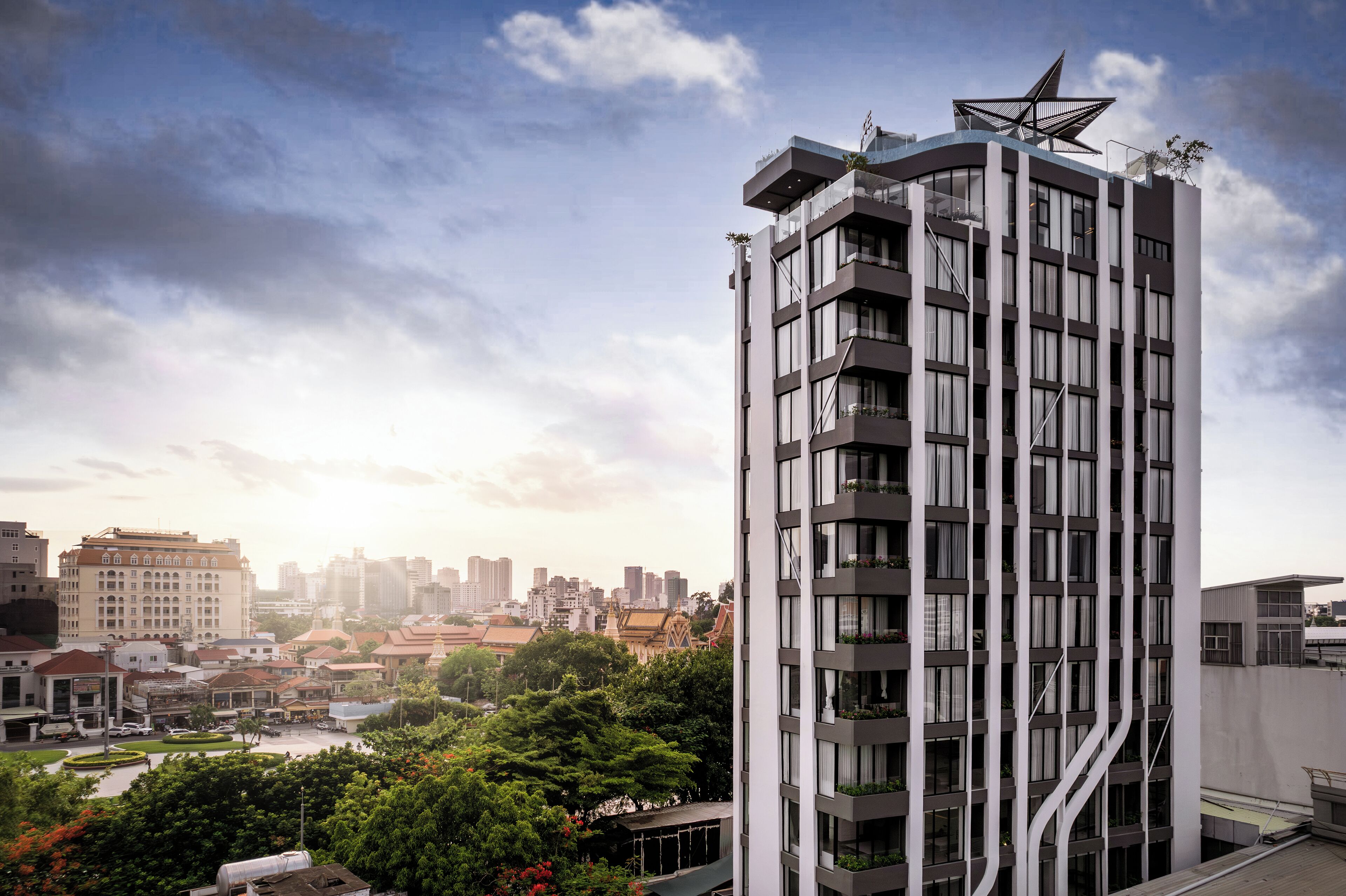 A modern high-rise building with a unique rooftop design, surrounded by a cityscape.