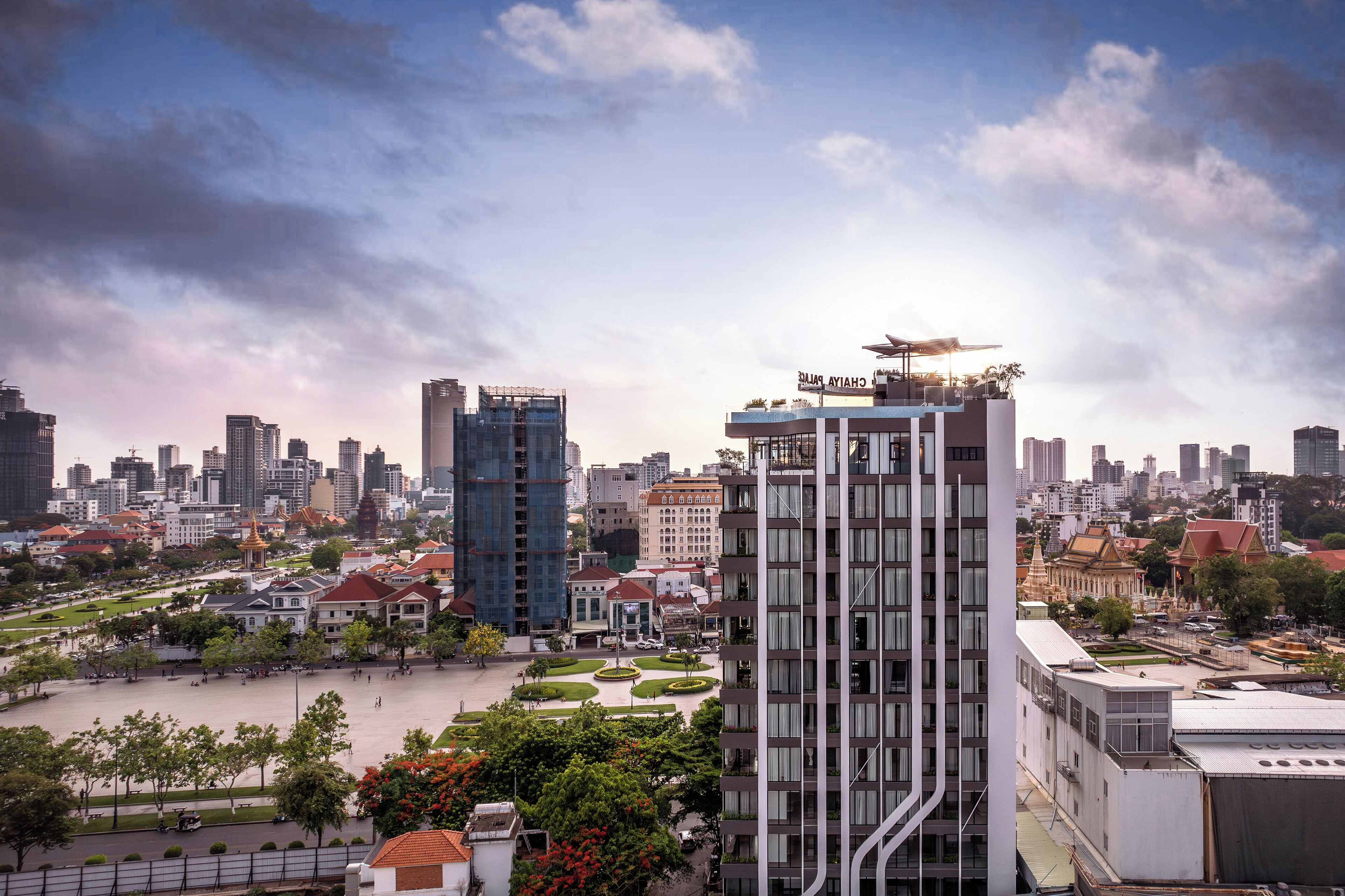 A high-rise building with a modern design, surrounded by a cityscape with various buildings and a large open plaza.