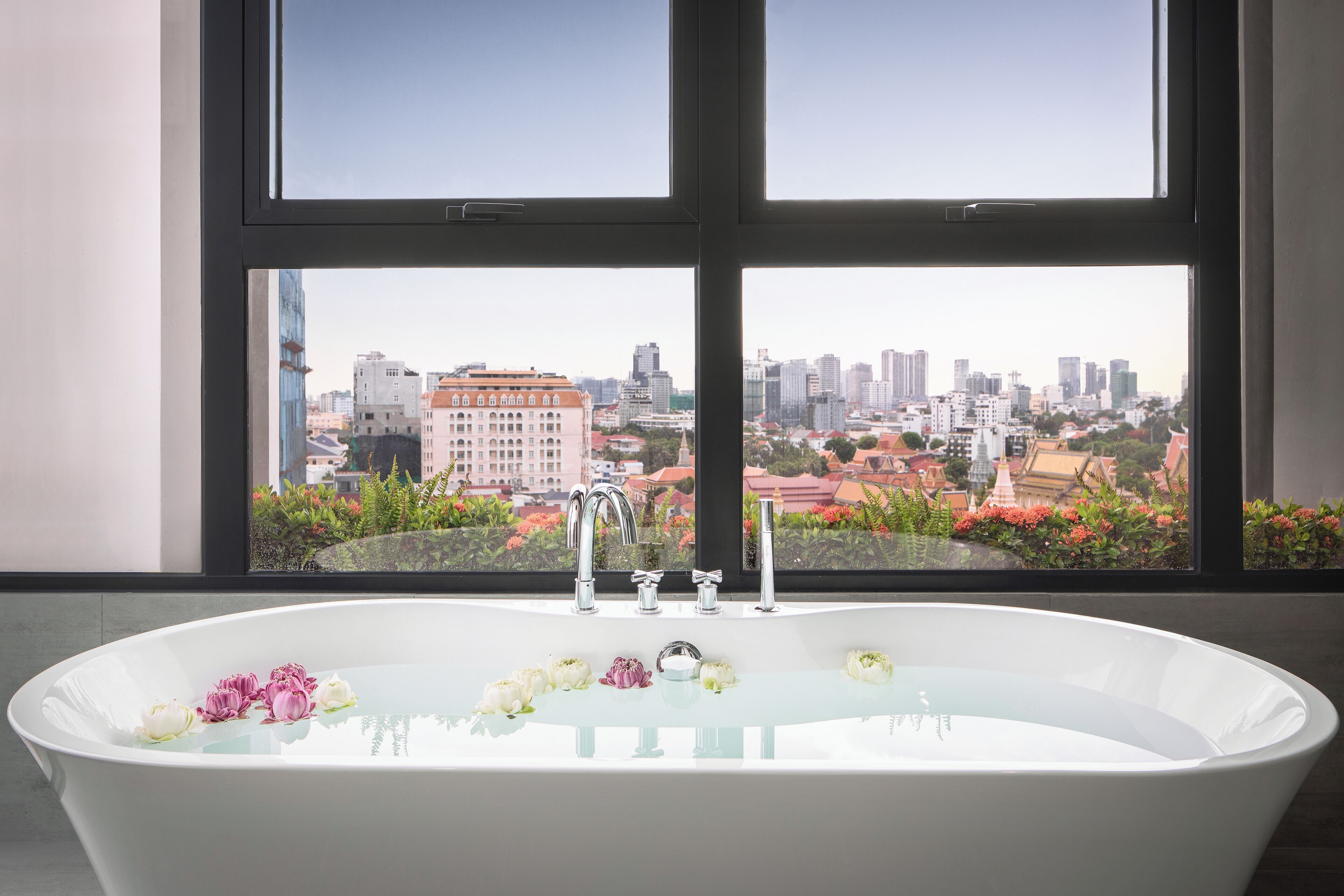 A bathroom with a bathtub, a window, and a city view.