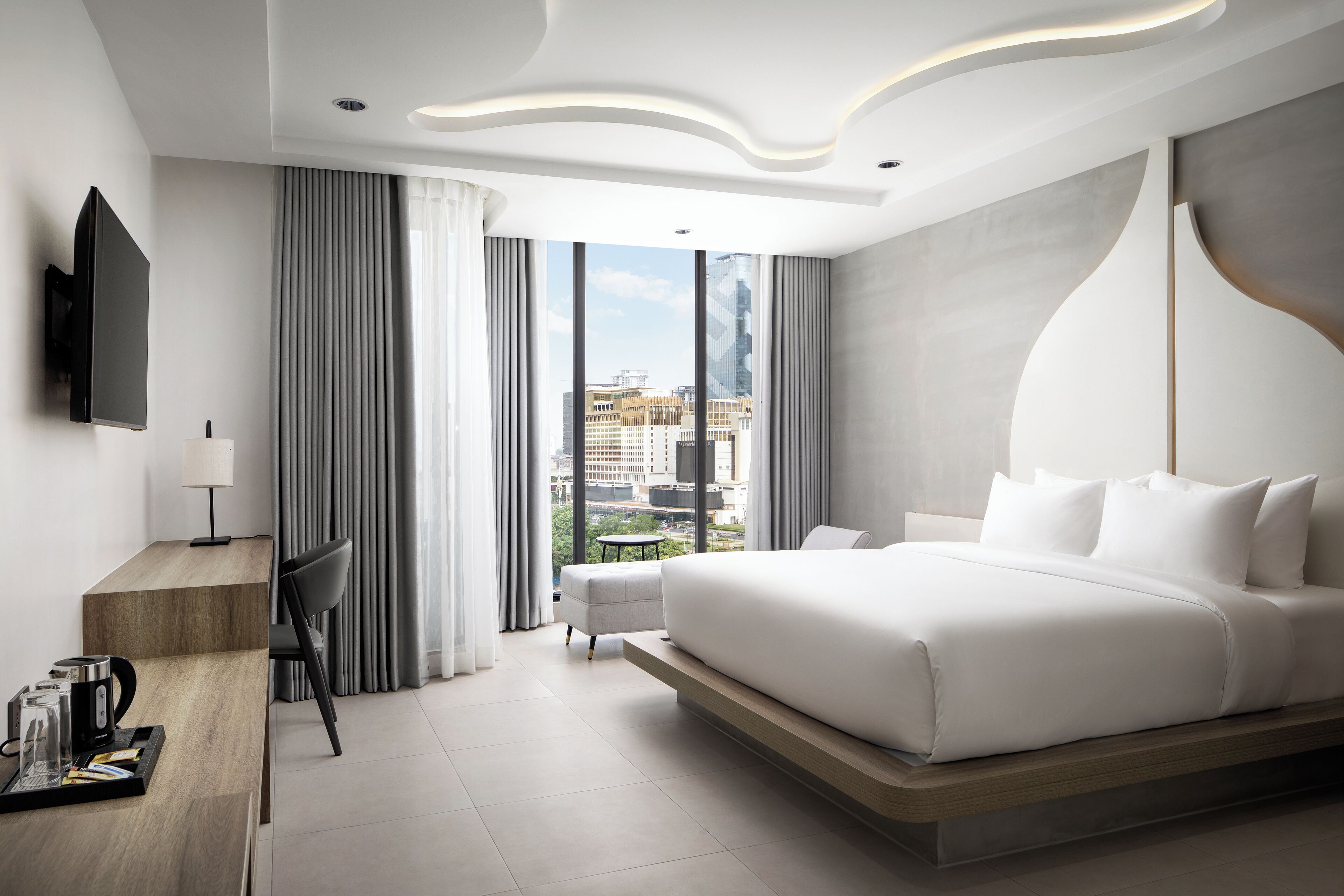 Een moderne hotelkamer met een groot bed, een bureau, een stoel en een televisie.