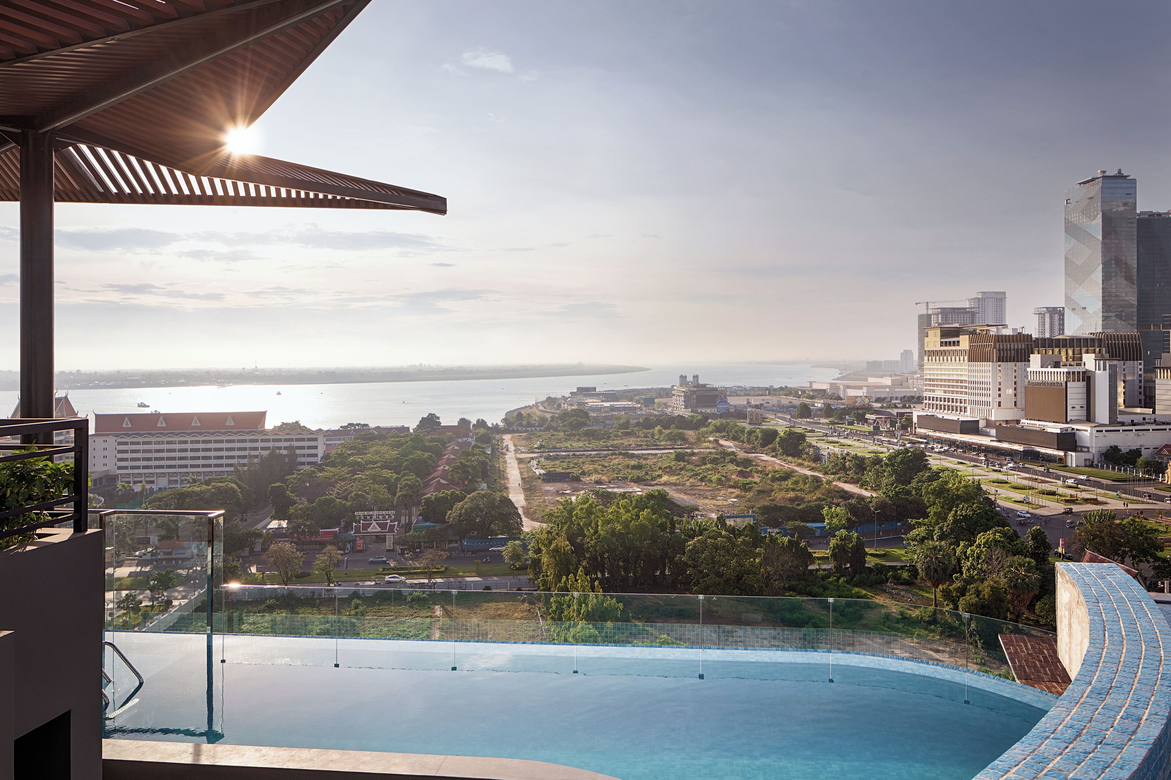 A rooftop pool with a city view, including a large building and a body of water.
