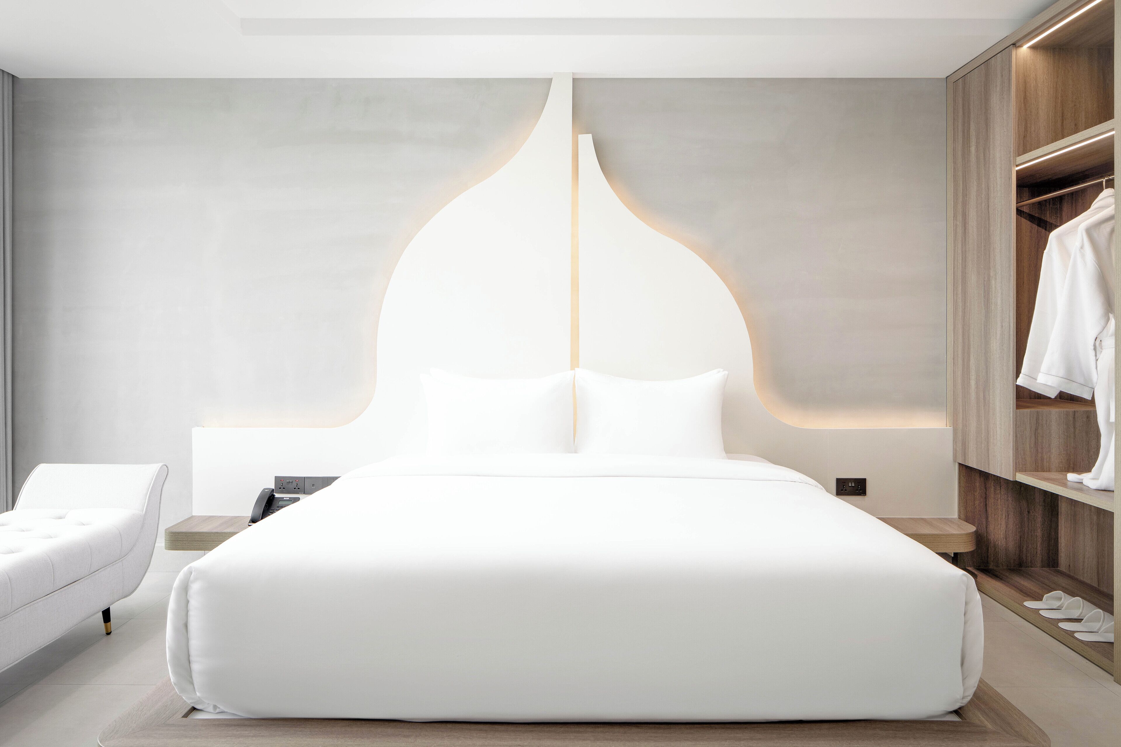 A modern bedroom with a large bed, bedside tables, a wardrobe, and a nightstand.