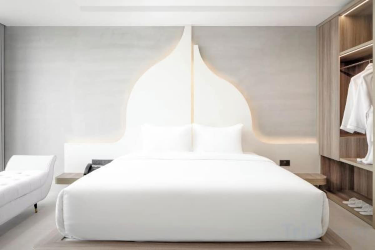 Una habitación de hotel moderna con una cama grande, mesitas de noche, un armario y un diseño de pared original.