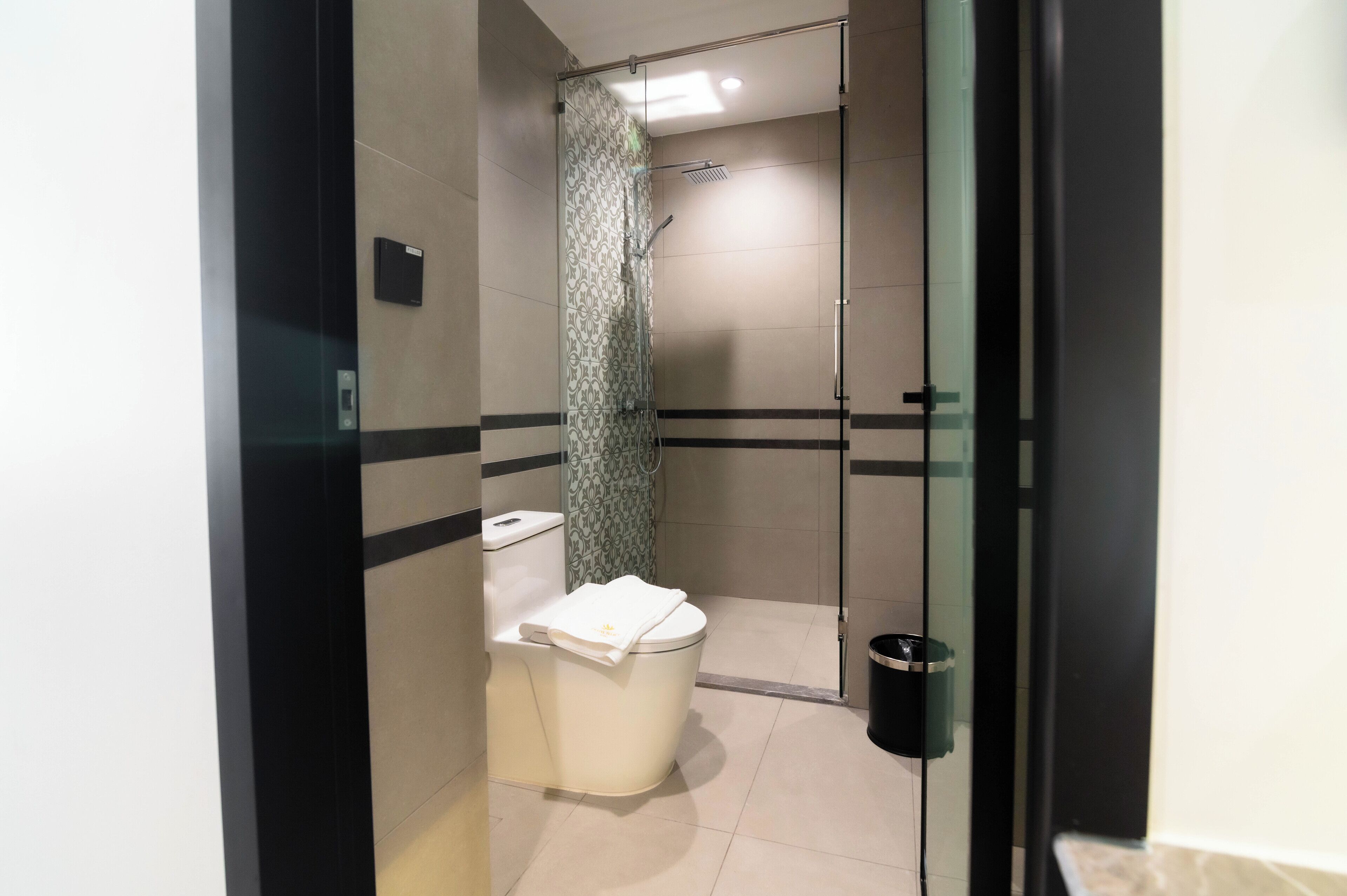 Une salle de bain moderne équipée de toilettes, d’une douche et d’une porte en verre.