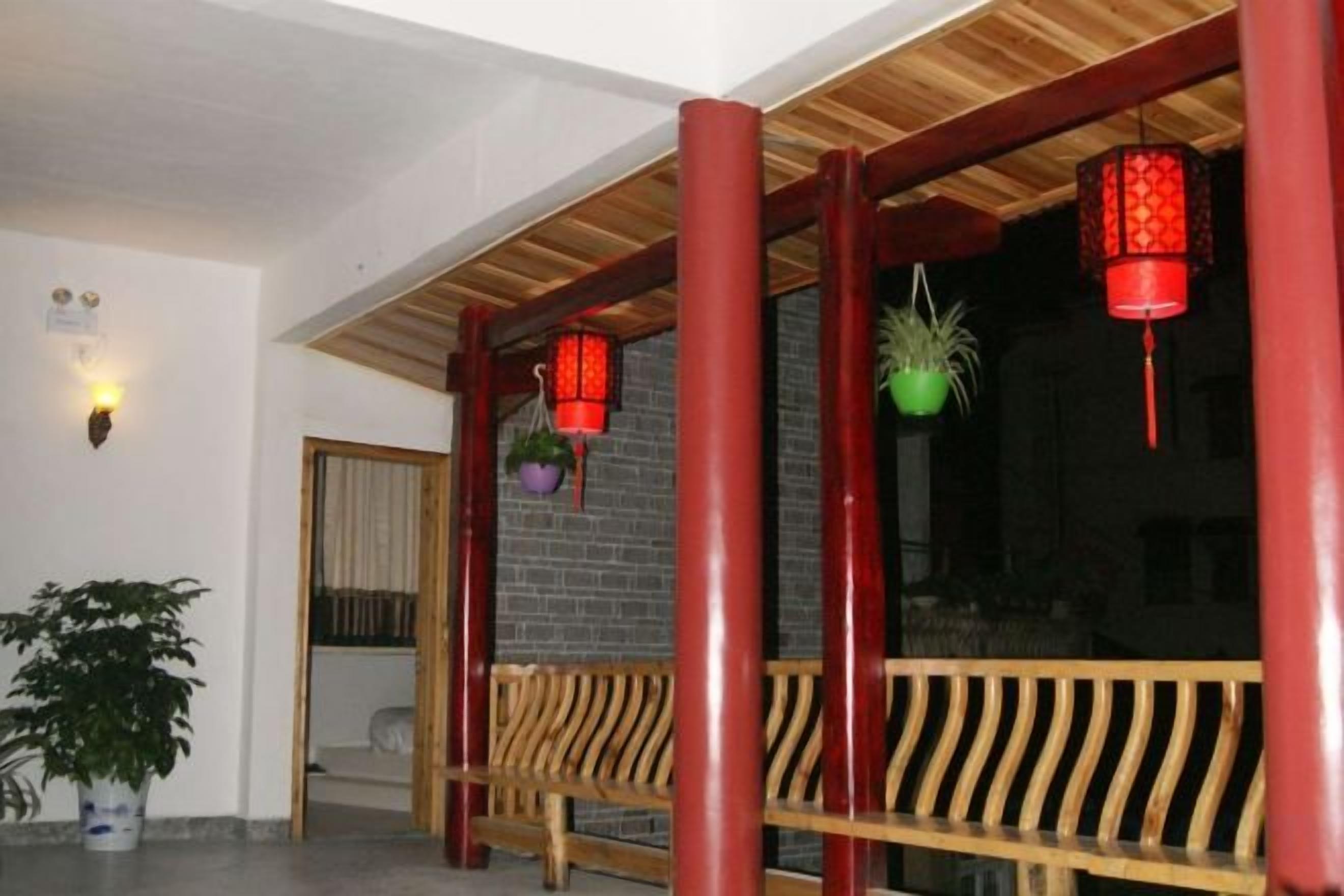 A wooden bench with a slatted design, a red lantern, and a potted plant.