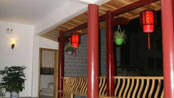 Un banco de madera con diseño de listones, un farol rojo y una planta en maceta.