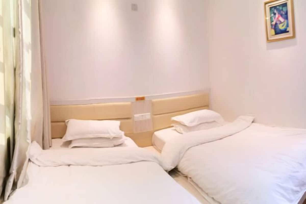 Een hotelkamer met twee bedden, een hoofdbord en een ingelijste foto aan de muur.