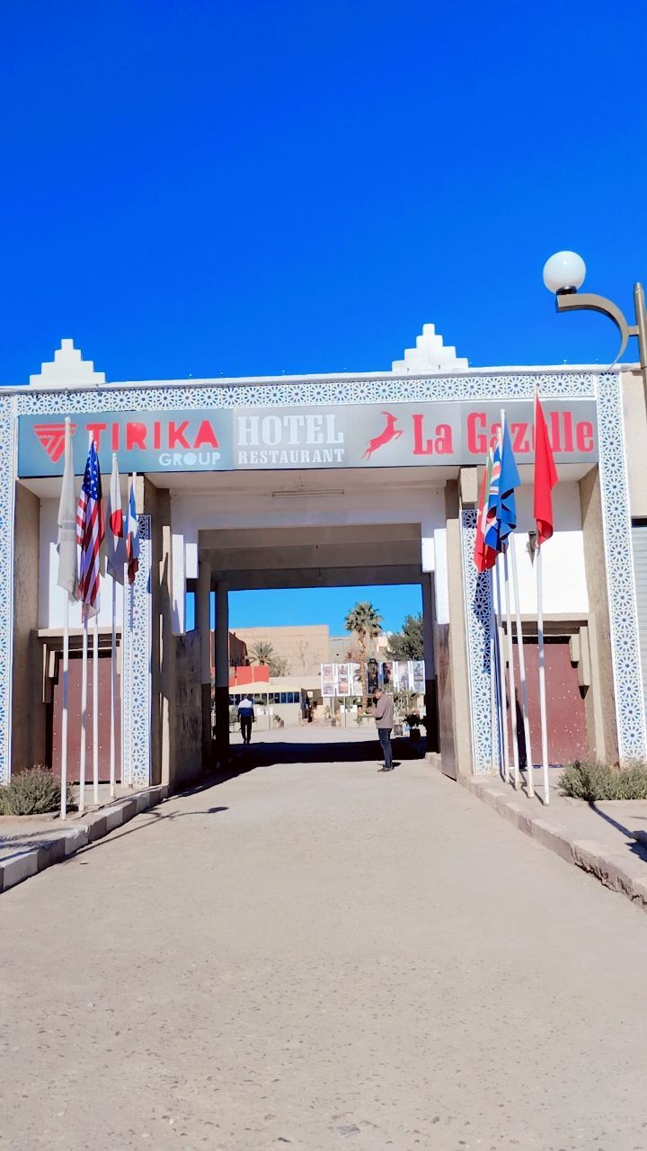 A hotel entrance with a sign reading "TIRIKA HOTEL RESTAURANT" and "La Gazelle".