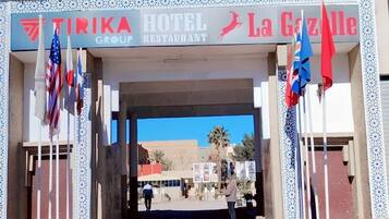 A hotel entrance with a sign reading "TIRIKA HOTEL RESTAURANT" and "La Gazelle".