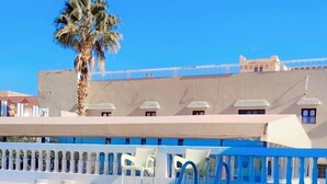 Una piscina azul cristalina con una palmera y un edificio al fondo.