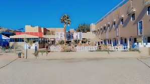 Un hotel con una hilera de habitaciones, una palmera y un cielo azul despejado.