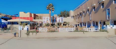 A hotel with a row of rooms, a palm tree, and a clear blue sky.
