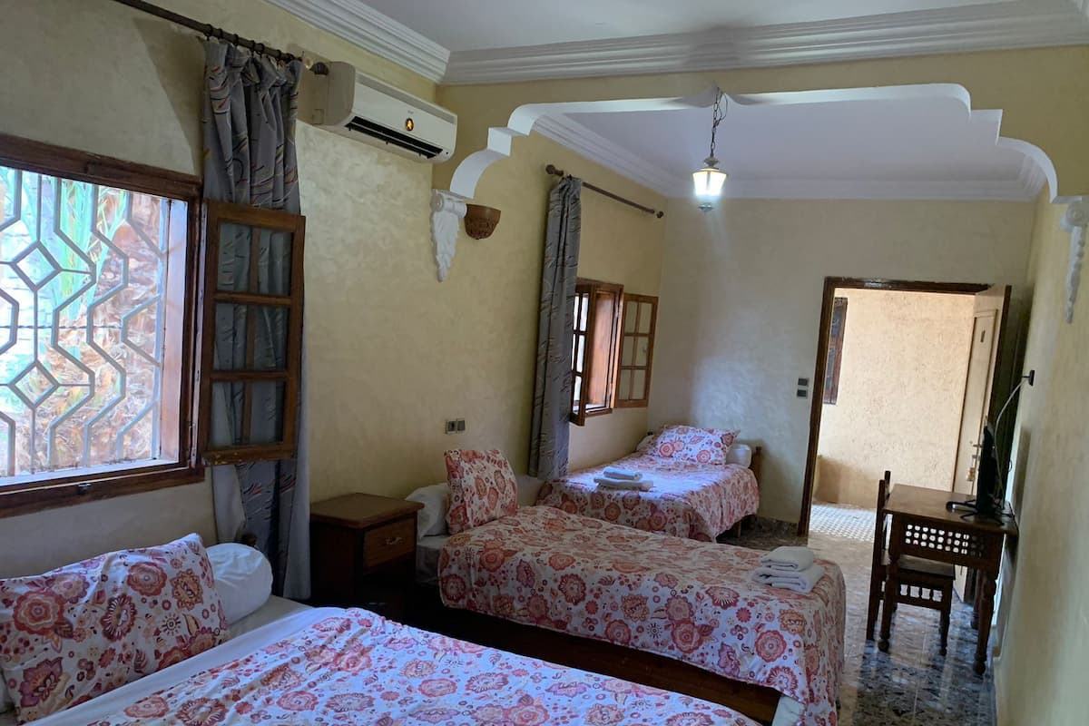 A room with two beds, a small table, and a chair.