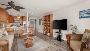 Ein geräumiges Wohnzimmer mit einem großen Flachbildfernseher, Holzmöbeln und einem Bücherregal.
